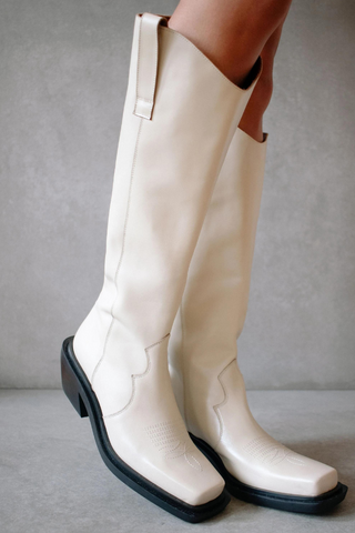 A Wild West inspired tall boot featuring classic cowgirl lining and an inverted midi heel.