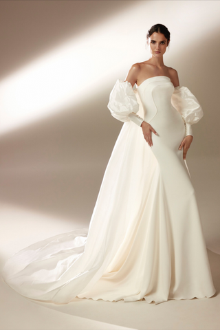 The Ford Wedding Dress by Bridal Designer Atelier Pronovias. Make your haute couture entrance in the dramatic sleeveless mermaid gown in flowing crepe and featuring sculptural panels. Accessorize with a taffeta cloak or coat by day, or bare seductive shoulders by night.