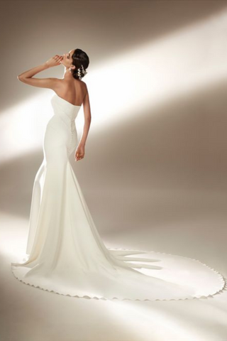 The Ford Wedding Dress by Bridal Designer Atelier Pronovias. Make your haute couture entrance in the dramatic sleeveless mermaid gown in flowing crepe and featuring sculptural panels. Accessorize with a taffeta cloak or coat by day, or bare seductive shoulders by night.