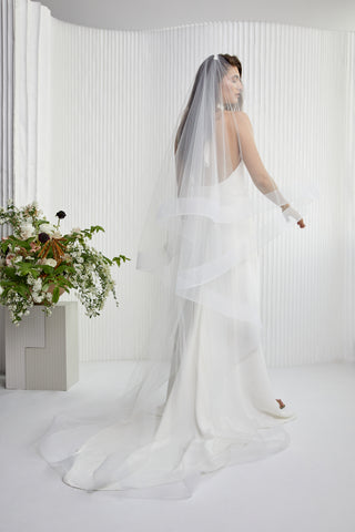 Here's a veil that glows up your bridal look. Hannah is special, she creates a voluminous halo of beauty around you making you radiant amongst your guests. She really is the perfect contemporary statement accessory. Cathedral Length with blusher, metal hair comb. Horse Hair Edge Veil (Sample in White)