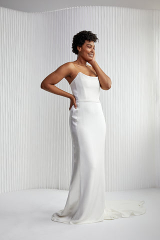 Vivian is our take on a classic strapless. She is a sleek gown with a modern, structured neckline. Vivian brings the drama, with a tuxedo satin silk stripe down the sides to accentuate your curves.  