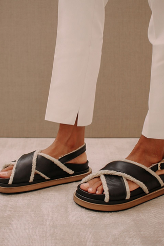 A 90s inspired oversized slipper leather sandal featuring a maxi double layered sole and a sherling covered inner straps. Criss-crossed front hold and a buckled back strap for added comfort. Designed by Alohas, and made in Spain. 