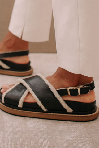 A 90s inspired oversized slipper leather sandal featuring a maxi double layered sole and a sherling covered inner straps. Criss-crossed front hold and a buckled back strap for added comfort. Designed by Alohas, and made in Spain. 