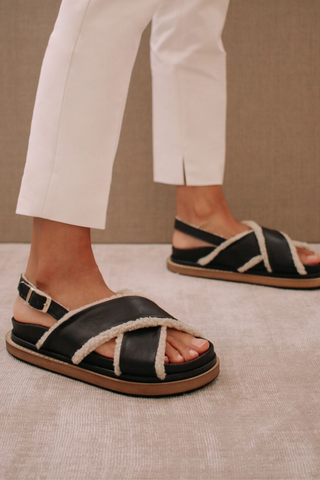 A 90s inspired oversized slipper leather sandal featuring a maxi double layered sole and a sherling covered inner straps. Criss-crossed front hold and a buckled back strap for added comfort. Designed by Alohas, and made in Spain. 