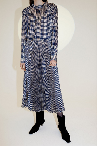 The Nima Dress is the dress for any occasion, designed by Birgitte Herskind. The fabric is a navy and white pepita check. It is pleated throughout and has a regular loose inspired silhouette. This piece doesn't need many accessories to make an impact, so style it simply with a sculptural ring or earrings.