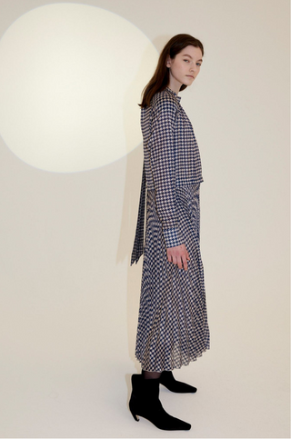 The Nima Dress is the dress for any occasion, designed by Birgitte Herskind. The fabric is a navy and white pepita check. It is pleated throughout and has a regular loose inspired silhouette. This piece doesn't need many accessories to make an impact, so style it simply with a sculptural ring or earrings.