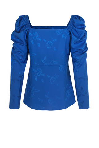 A vibrant blue feminine blouse with a squared neckline and puff sleeves in a cool rose weaved fabric. Made from 100% recycled polyester made from plastic waste. Pair with high-waisted trousers or a skirt for any occasion or event! Cras only uses certified sustainable and natural fabrics, which reduces the footprint of our products immensely. The fabrics range from certified recycled polyester, the new “green“ type of viscose Eco Vero, natural silk and organic cotton. 