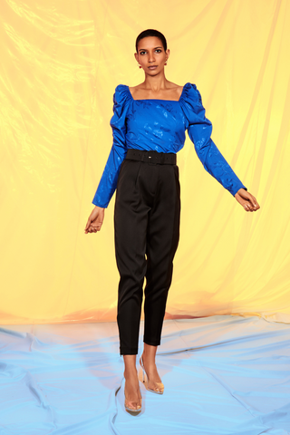 A vibrant blue feminine blouse with a squared neckline and puff sleeves in a cool rose weaved fabric. Made from 100% recycled polyester made from plastic waste. Pair with high-waisted trousers or a skirt for any occasion or event! Cras only uses certified sustainable and natural fabrics, which reduces the footprint of our products immensely. The fabrics range from certified recycled polyester, the new “green“ type of viscose Eco Vero, natural silk and organic cotton. 