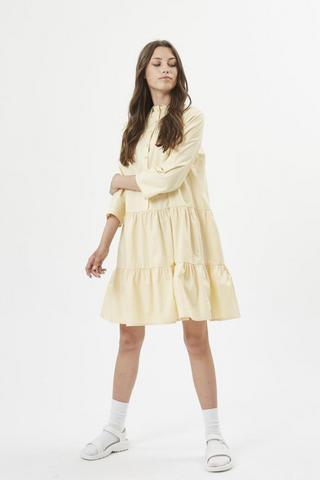 The Skalina Dress by Minimum is a lightweight summer dream dress made from 100% cotton. Detailed with a soft oversized lace collar, and delicate upholstered buttons down the front towards the waist. Perfect for all of your summer plans and Sunday brunches, we love the ruffled details of the skirt of this dress. 